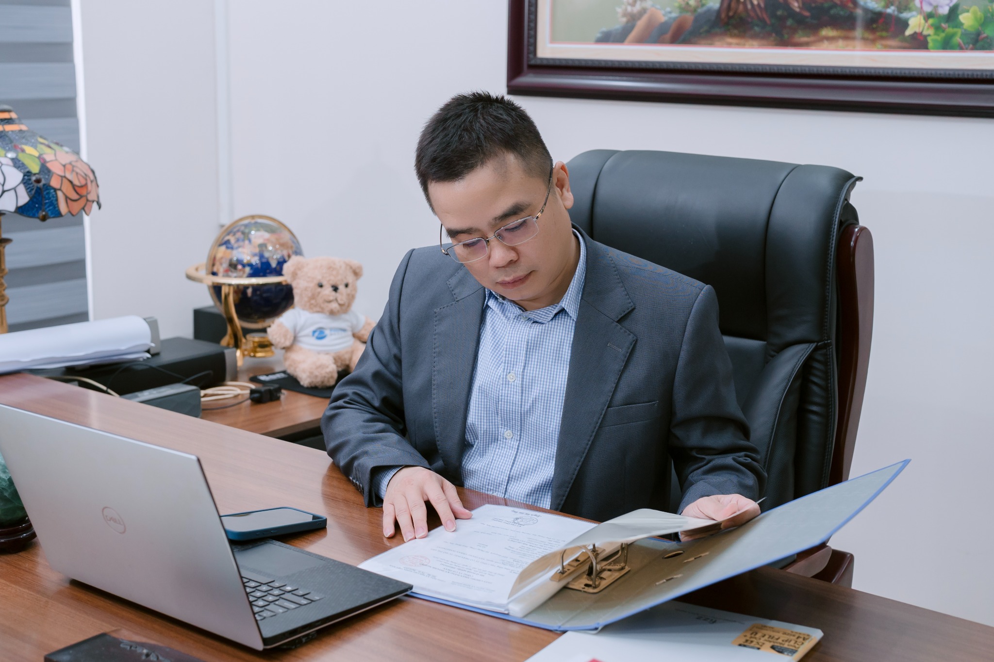 Binh Ba Ngo reviewing documents at his desk beside a laptop.